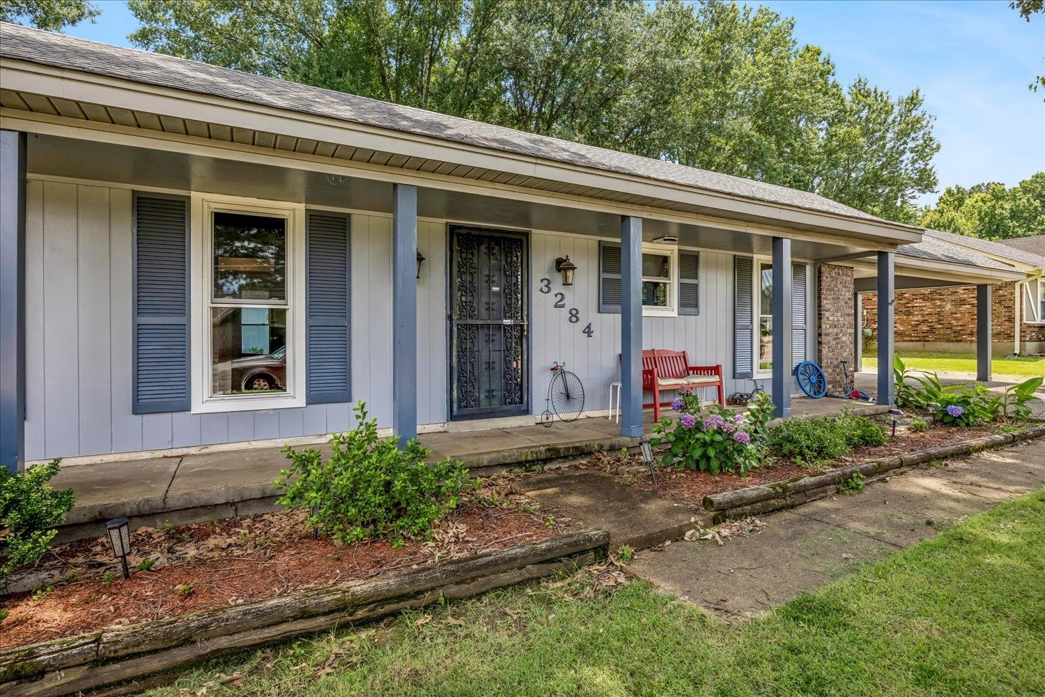 3284 Altruria Road Bartlett, TN 38134 - Photo 5 of 28 Front exterior featuring light gray siding with blue-gray shutters, a covered porch with supporting columns, and a stone accent wall