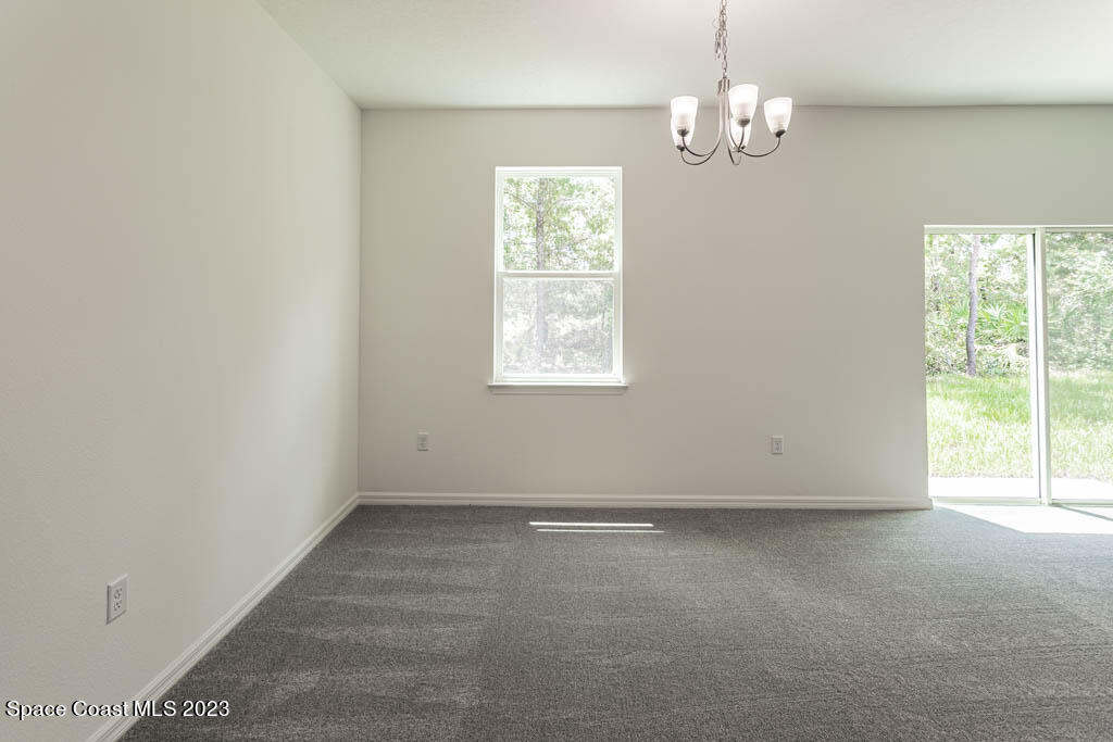174 Compass Titusville, FL 32796 - Photo 13 of 32 en empty room with windows and chandelier