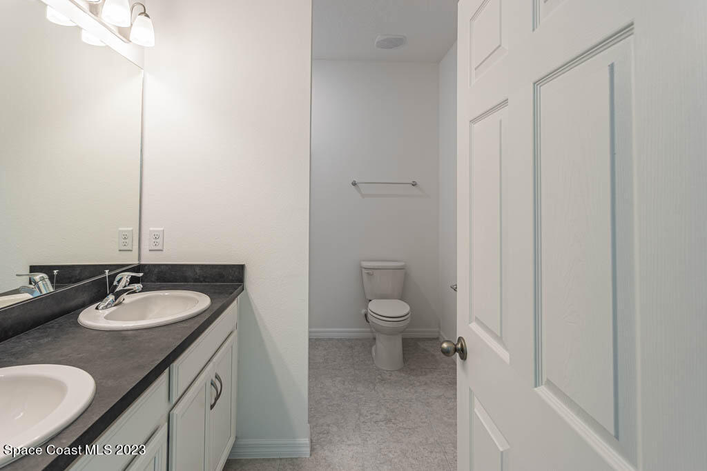 174 Compass Titusville, FL 32796 - Photo 19 of 32 a bathroom with a granite countertop sink toilet and mirror