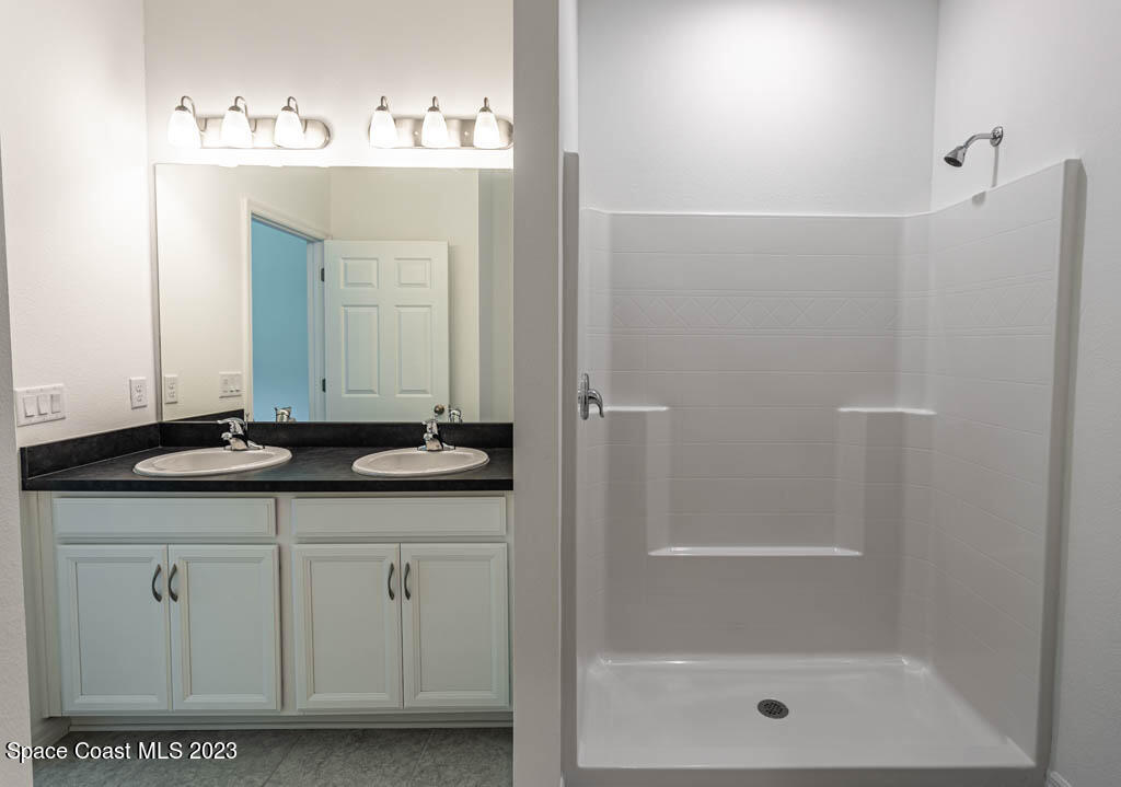 174 Compass Titusville, FL 32796 - Photo 22 of 32 a bathroom with a granite countertop sink a mirror and a shower