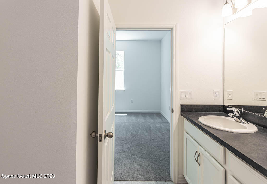 174 Compass Titusville, FL 32796 - Photo 24 of 32 a bathroom with a granite countertop sink and a mirror
