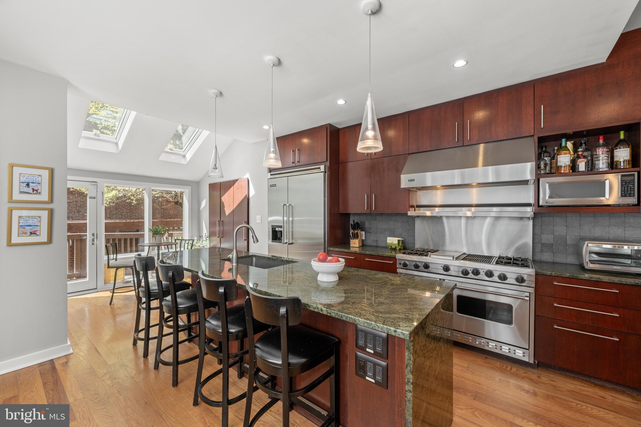 303 Spruce Street Philadelphia, PA 19106 - Photo 8 of 30 a kitchen with stainless steel appliances granite countertop a stove a refrigerator a kitchen island a dining table and chairs with wooden floor