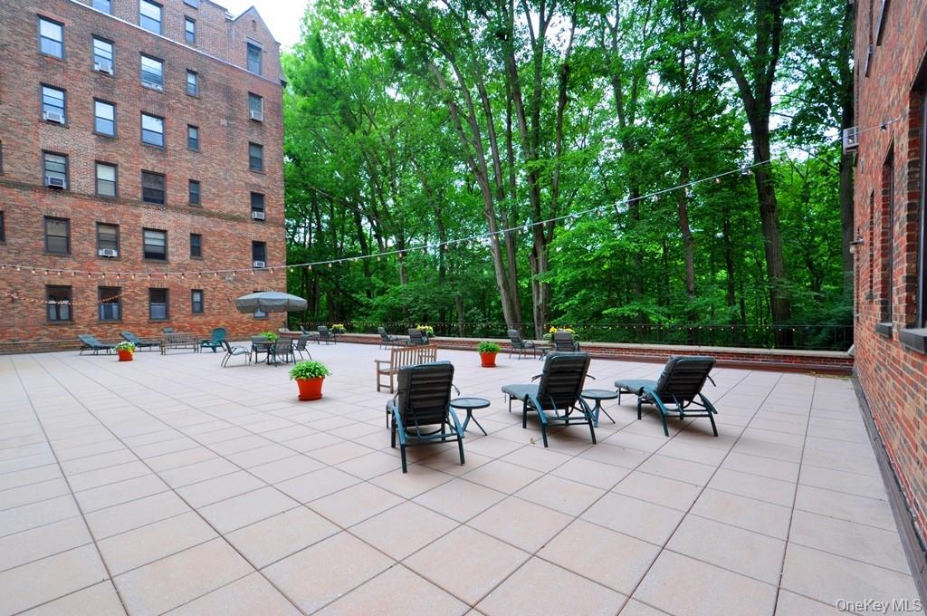 143 Garth Road, Unit 5J Scarsdale, NY 10583 - Photo 35 of 47 a view of pool with outdoor seating and trees