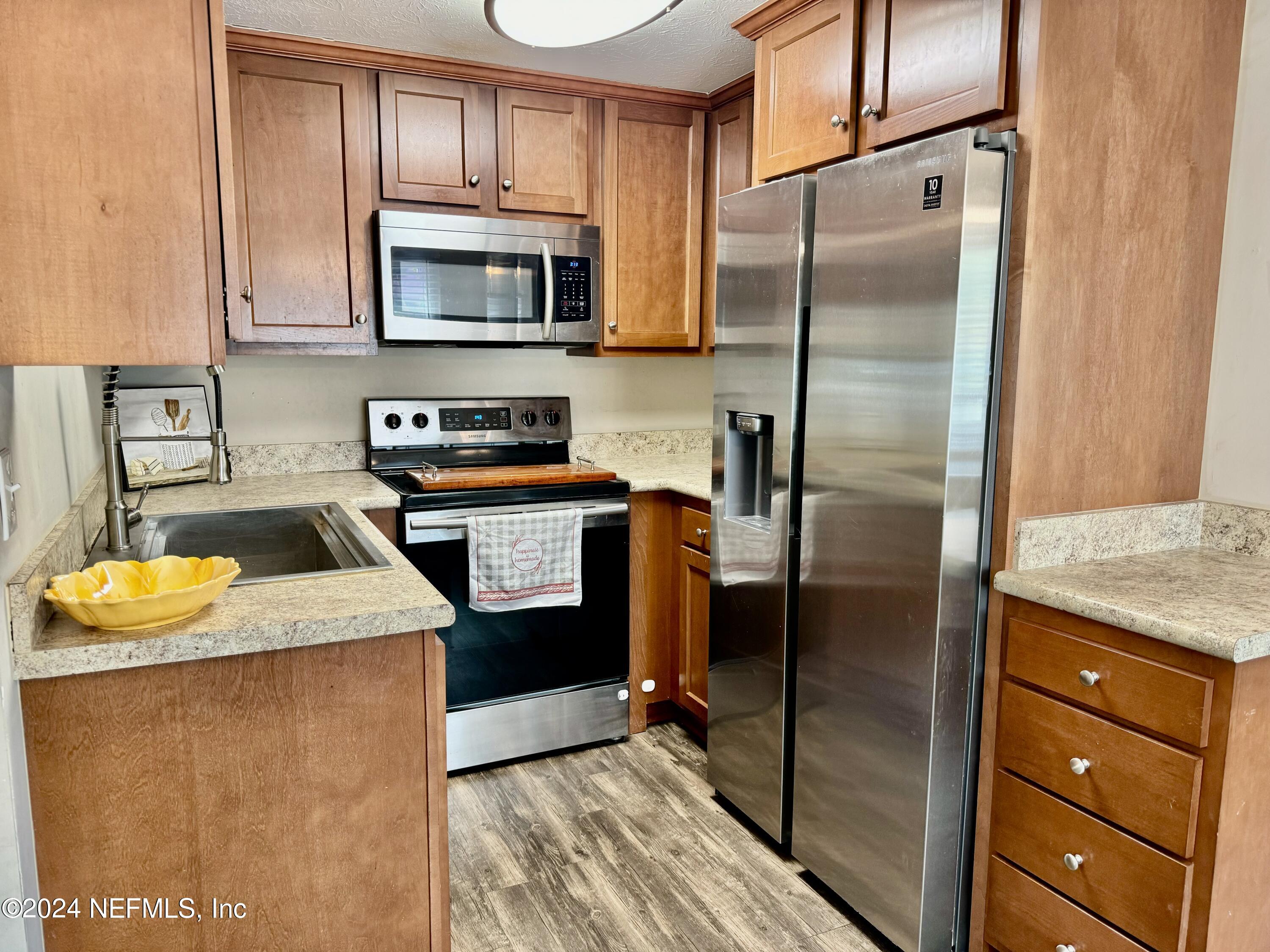 398 Gwinnett Road Orange Park, FL 32073 - Photo 11 of 40 a kitchen with stainless steel appliances granite countertop a refrigerator a stove and a sink with wooden floor