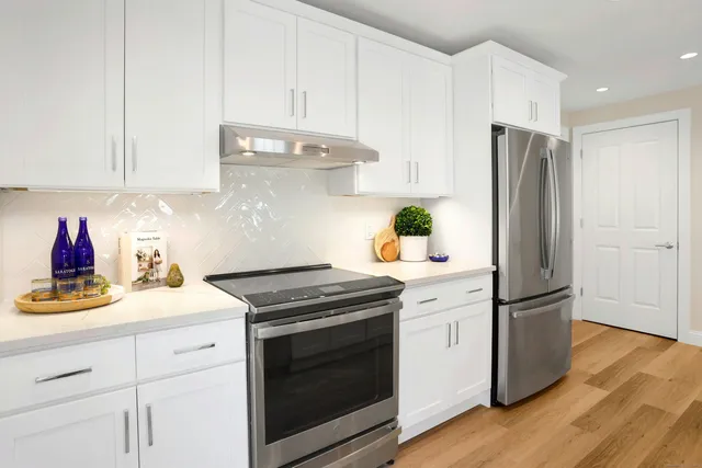 a kitchen with stainless steel appliances white cabinets and a refrigerator