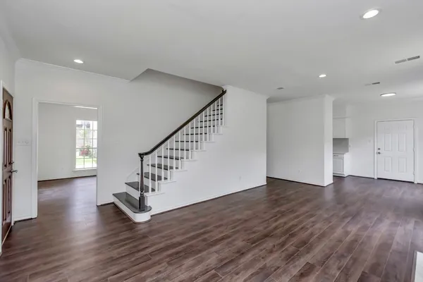 an empty room with wooden floor fireplace and windows