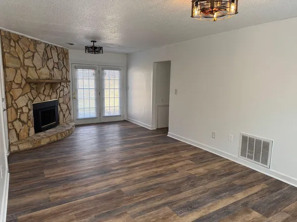 an empty room with wooden floor fireplace and windows