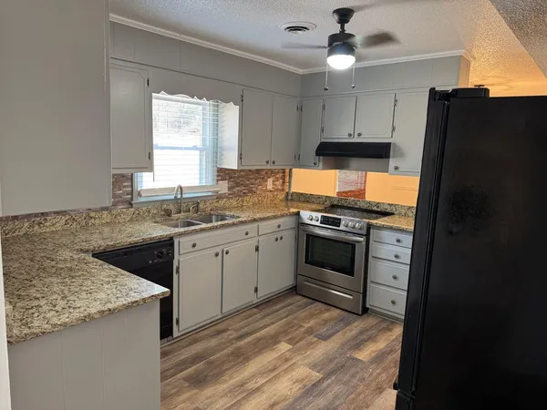 a kitchen with granite countertop stainless steel appliances a stove cabinets and a refrigerator