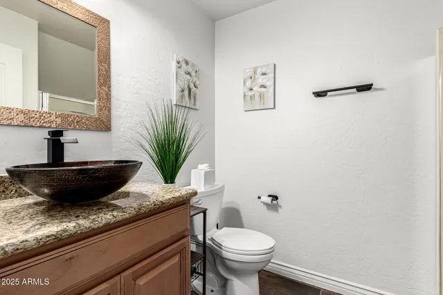 a bathroom with a granite countertop sink a toilet and mirror