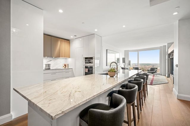 a large kitchen with kitchen island white cabinets and stainless steel appliances