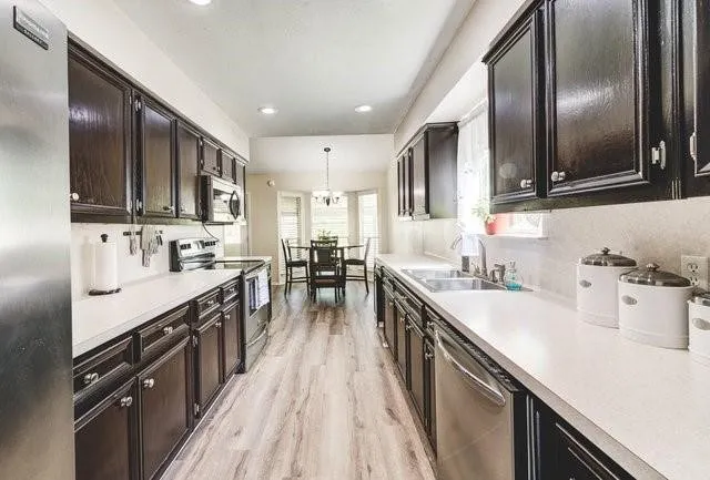 a large kitchen with stainless steel appliances sink a stove and cabinets