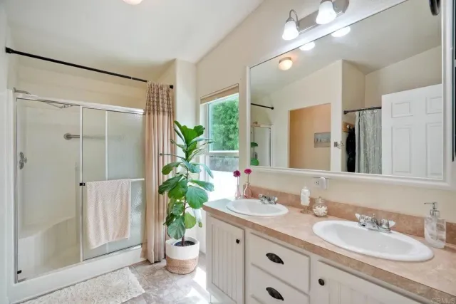 a bathroom with a granite countertop sink a toilet a large mirror and shower