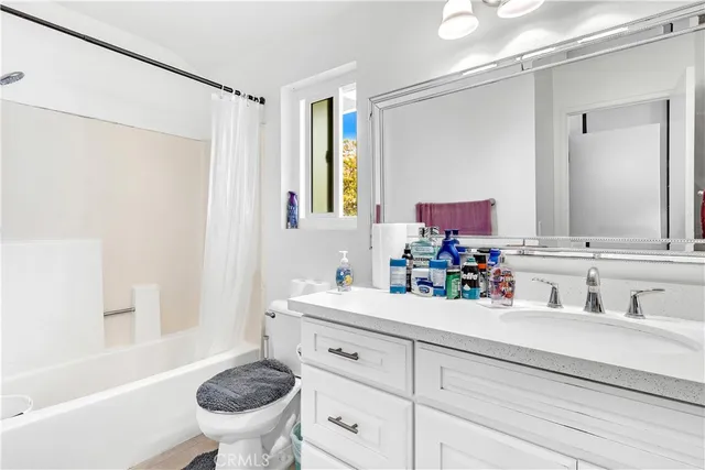 a bathroom with a bathtub shower sink vanity mirror and toilet