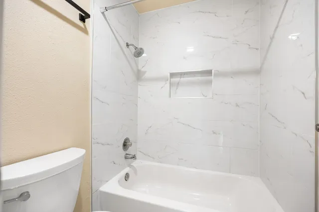 a white bath tub sitting next to a white toilet and vanity