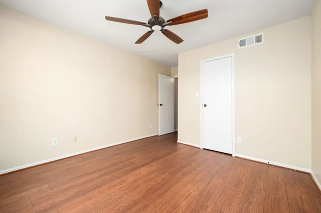 an empty room with wooden floor and a ceiling fan