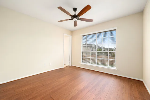 an empty room with wooden floor and ceiling fan