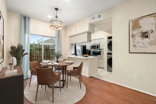 a dining room with wooden floor a chandelier a glass table and chairs