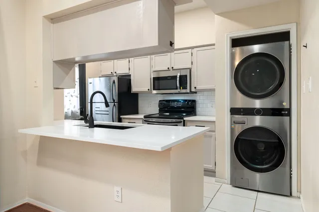 a kitchen with stainless steel appliances a sink a stove a washer and dryer
