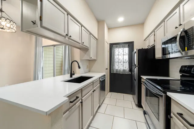 a kitchen with stainless steel appliances a sink dishwasher a stove a refrigerator and cabinets