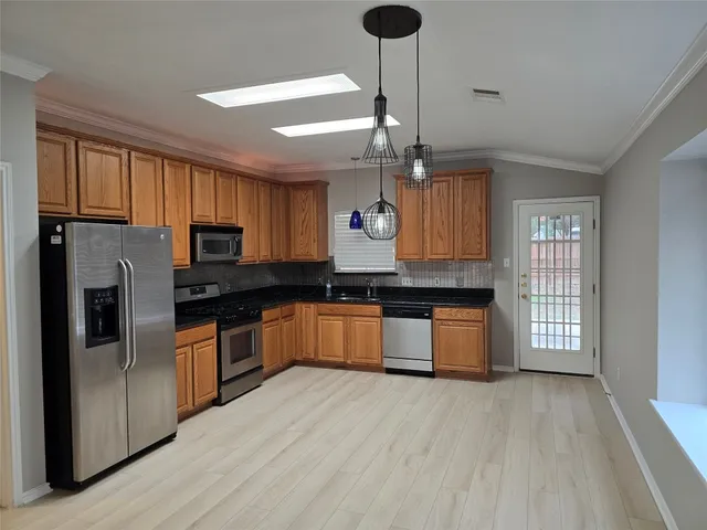 a kitchen with stainless steel appliances granite countertop a refrigerator a sink dishwasher a stove and a oven with wooden floor