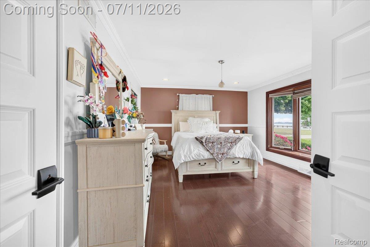 23750 East River Road Grosse Ile, MI 48138 - Photo 18 of 54 Bedroom featuring rich wood-finish flooring, a neutral color palette with accent wall, and crown molding