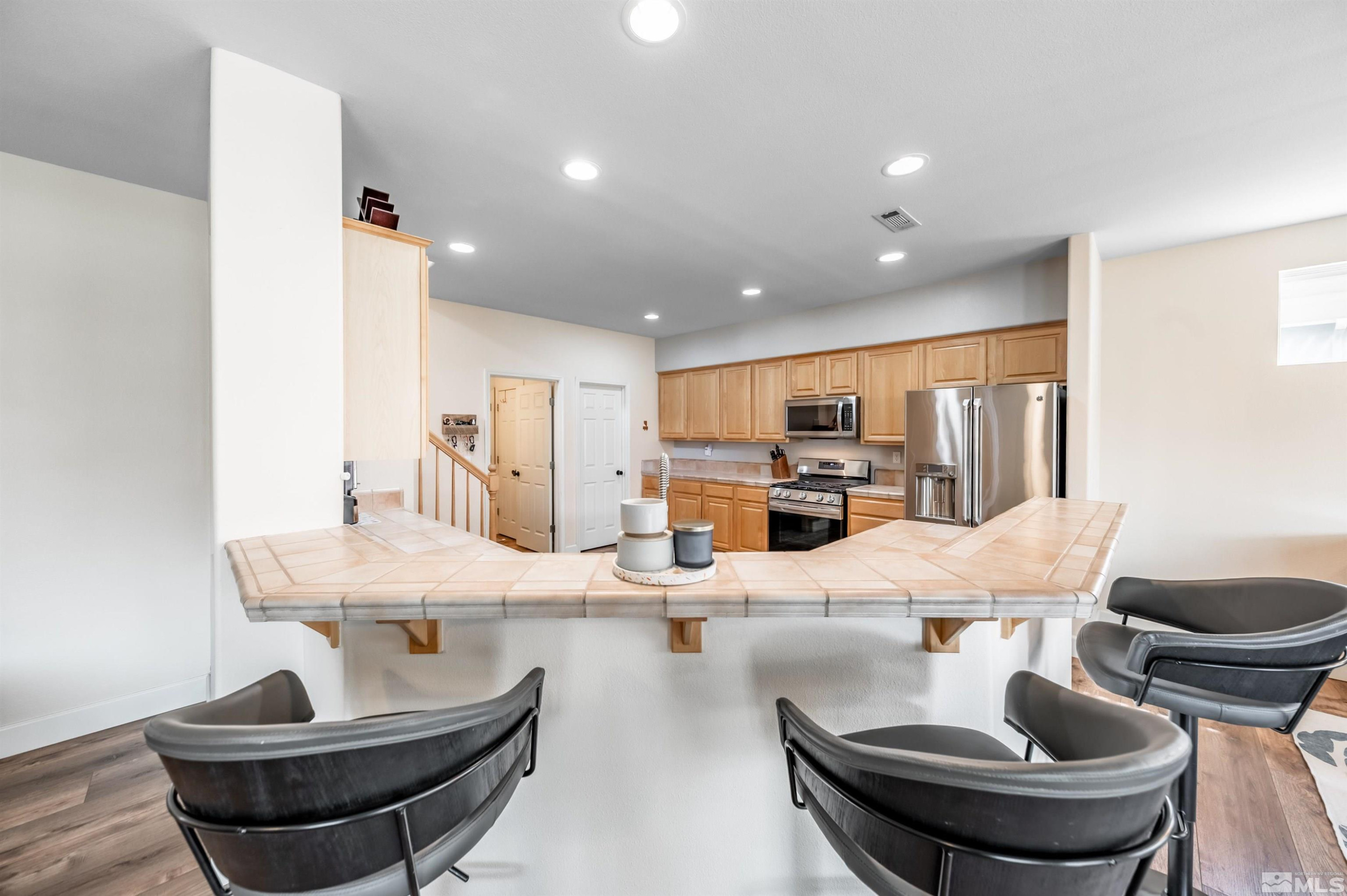 9915 Bandana Way Reno, NV 89521 - Photo 12 of 40 a kitchen with stainless steel appliances kitchen island granite countertop a dining table and chairs