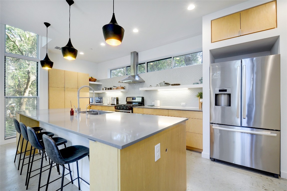 a kitchen with stainless steel appliances granite countertop a sink a refrigerator and a stove