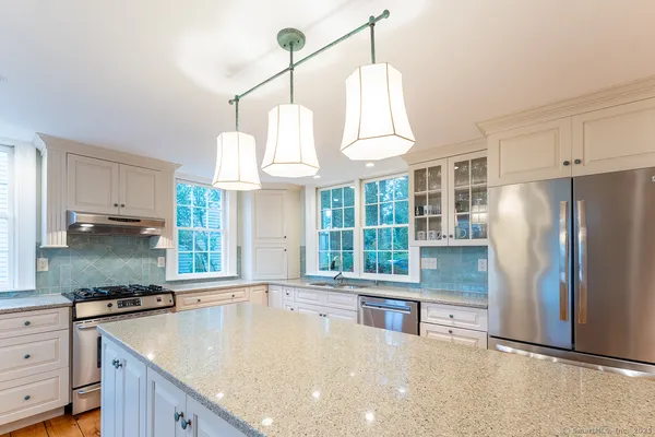 a kitchen with granite countertop a sink a counter space appliances and cabinets
