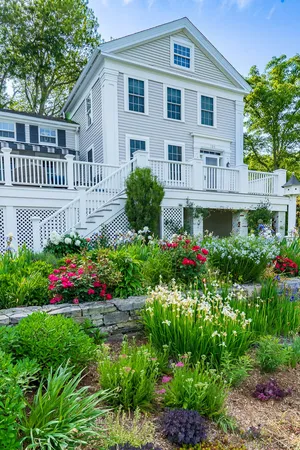 a front view of a house with a flower garden and flower plants