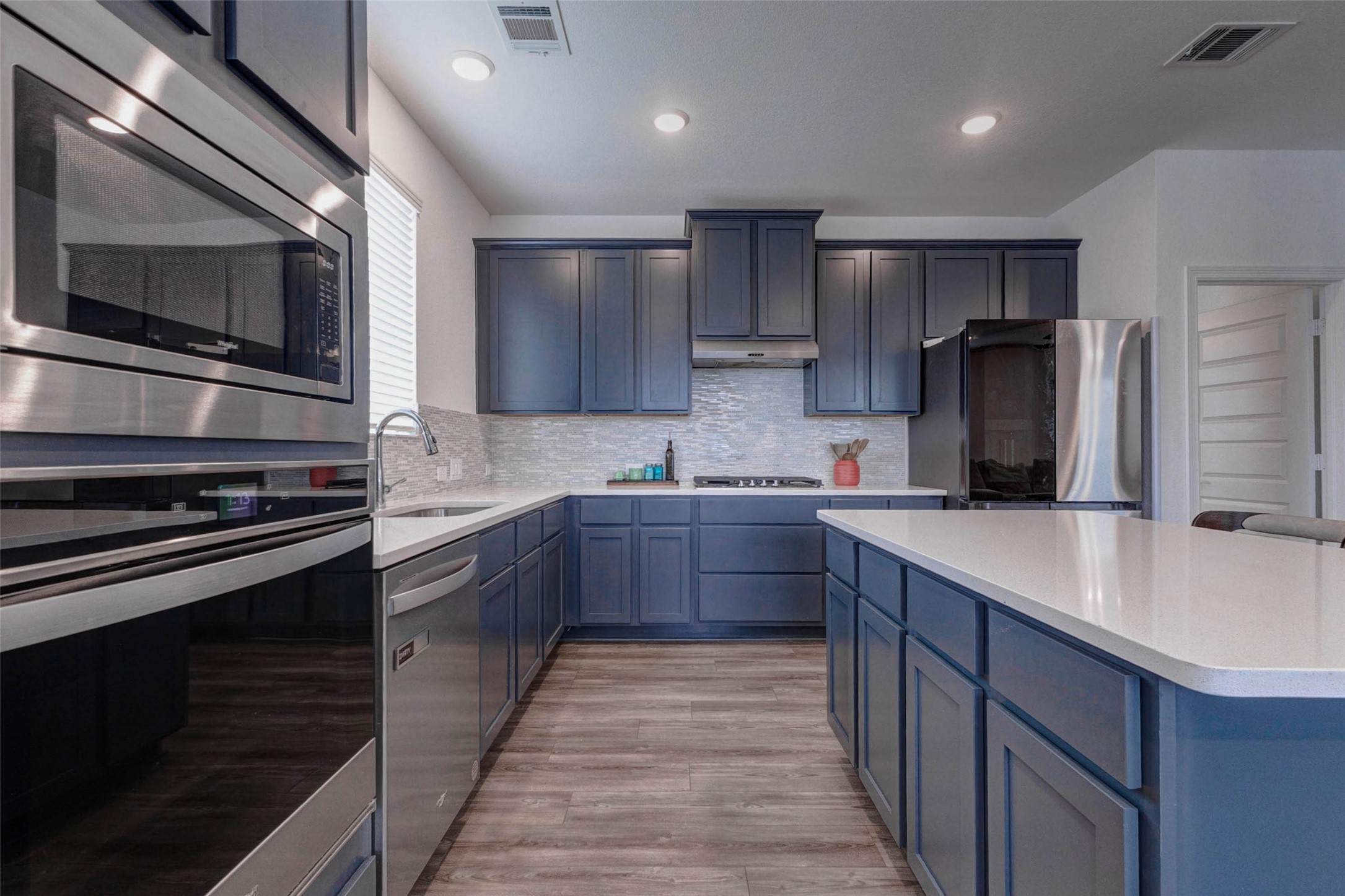 32418 Fly Fish Way Fulshear, TX 77441 - Photo 9 of 40 This angle highlights the full suite of stainless steel appliances, including the built-in microwave and double oven, while also showcasing the expansive island with ample cabinet and drawer storage below. The striking cabinetry paired with crisp white countertops gives this kitchen a designer feel that is truly one of the home's standout features.