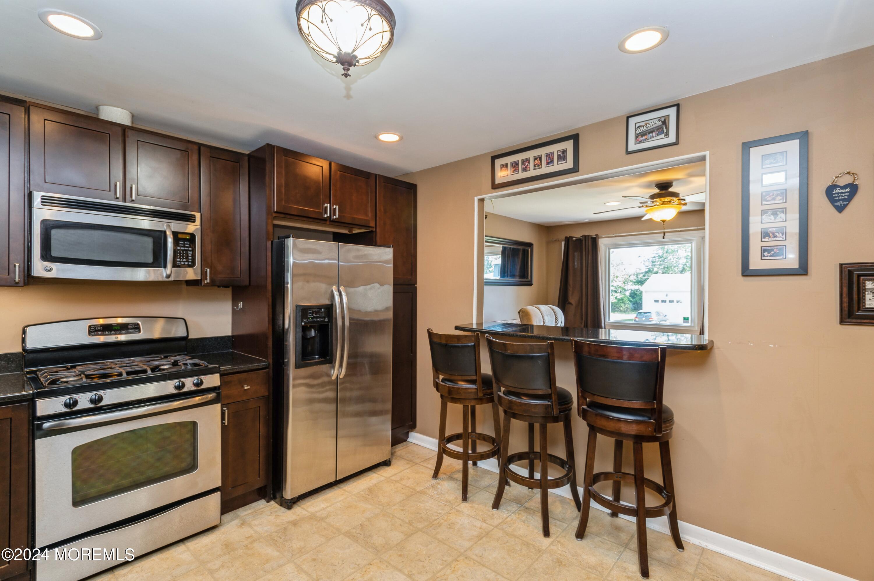 62 Capri Drive Brick, NJ 08723 - Photo 11 of 22 a kitchen with stainless steel appliances granite countertop a stove top oven a sink dishwasher a dining table and chairs with wooden floor