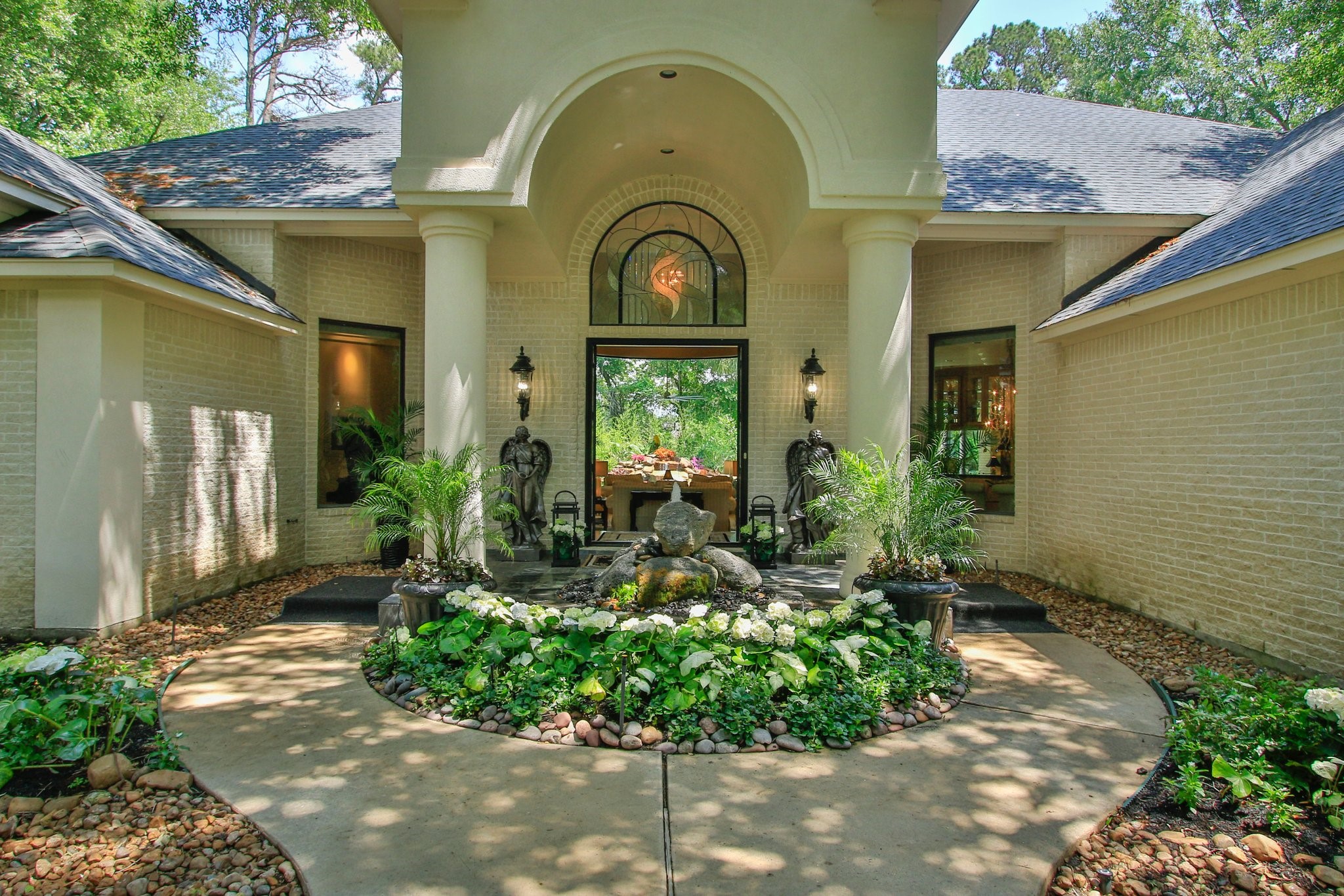 17511 Seidel Road Tomball, TX 77377 - Photo 46 of 49 This elegant home features a grand entrance with a landscaped walkway, lush greenery, and a decorative fountain centerpiece, framed by white brick and large columns for a welcoming and luxurious curb appeal.