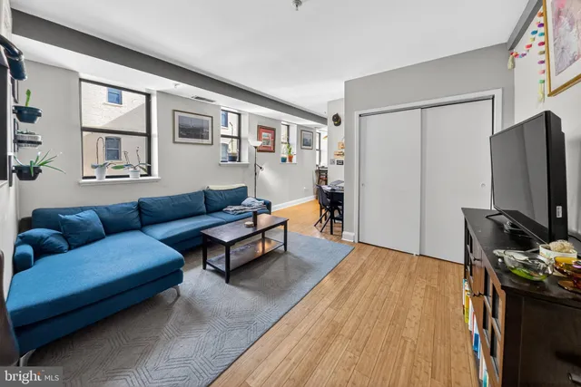 a living room with furniture a flat screen tv and a refrigerator