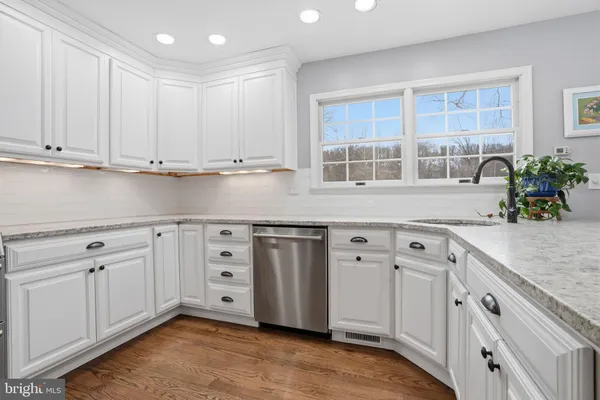 a kitchen with stainless steel appliances granite countertop a sink and cabinets with wooden floor