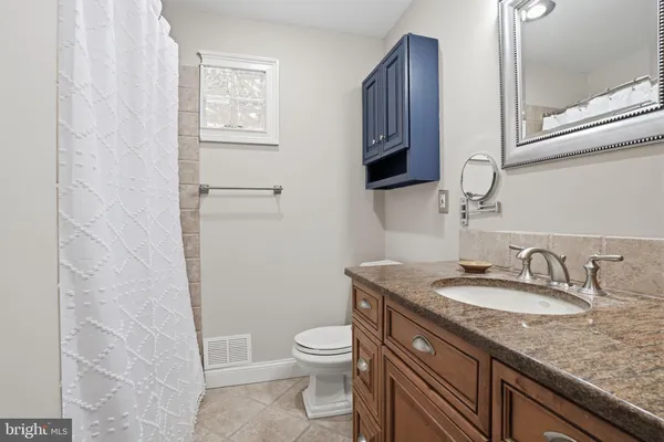 a bathroom with a granite countertop toilet a sink and a mirror