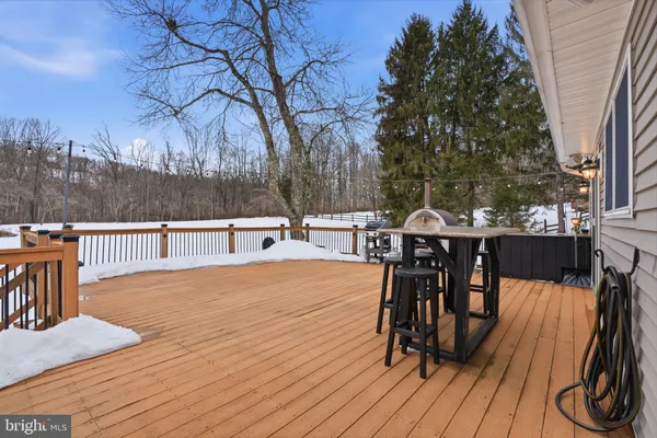 a view of a roof deck with table and chairs couches and a barbeque with wooden fence and floor