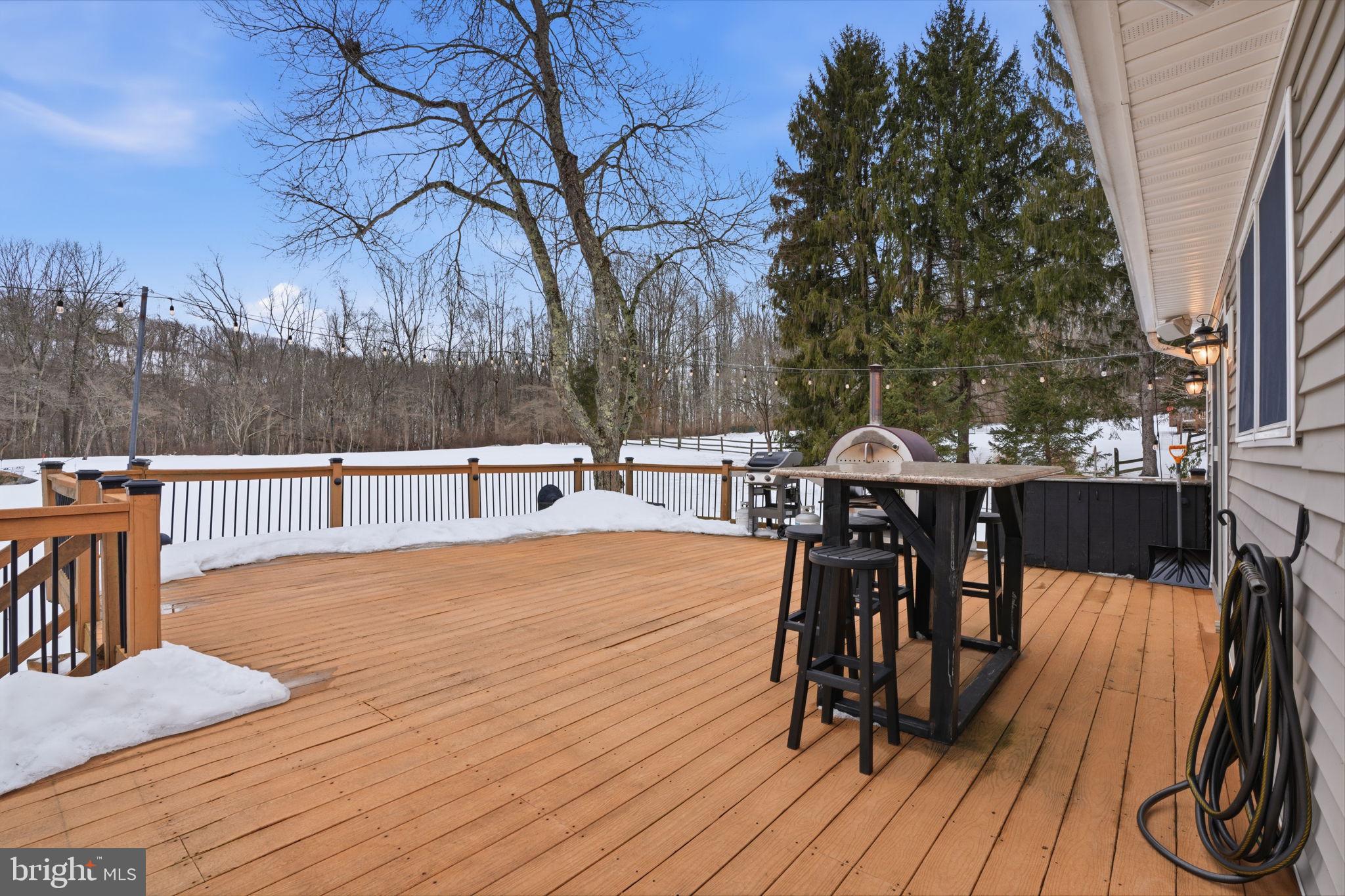 521 Cokesbury Road Annandale, NJ 08801 - Photo 32 of 56 a view of a roof deck with table and chairs couches and a barbeque with wooden fence and floor