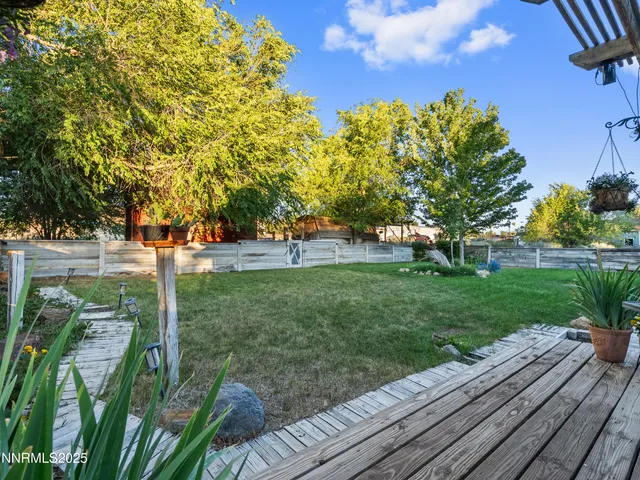 a view of a backyard with wooden fence and a large tree