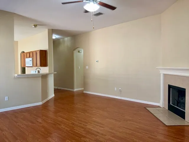 a view of an empty room with window and wooden floor