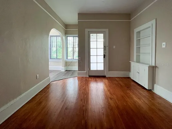 an empty room with wooden floor and windows