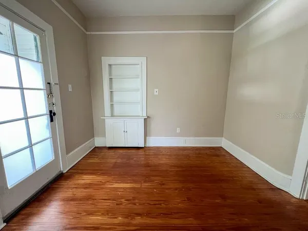 a view of an empty room with wooden floor and a window