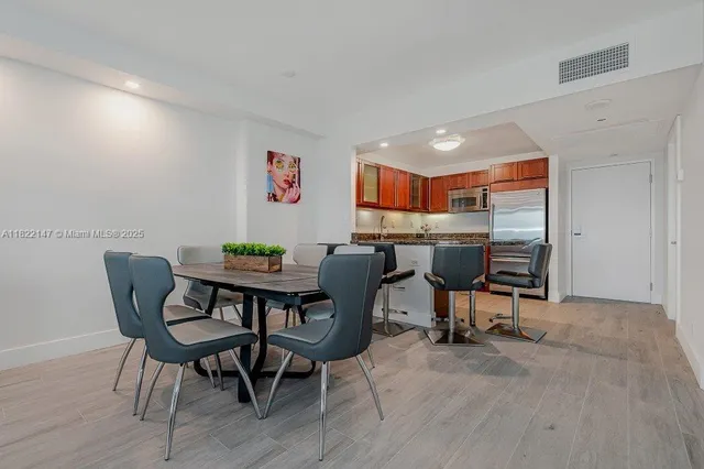 a kitchen with stainless steel appliances granite countertop a stove top oven a sink a dining table and chairs with wooden floor