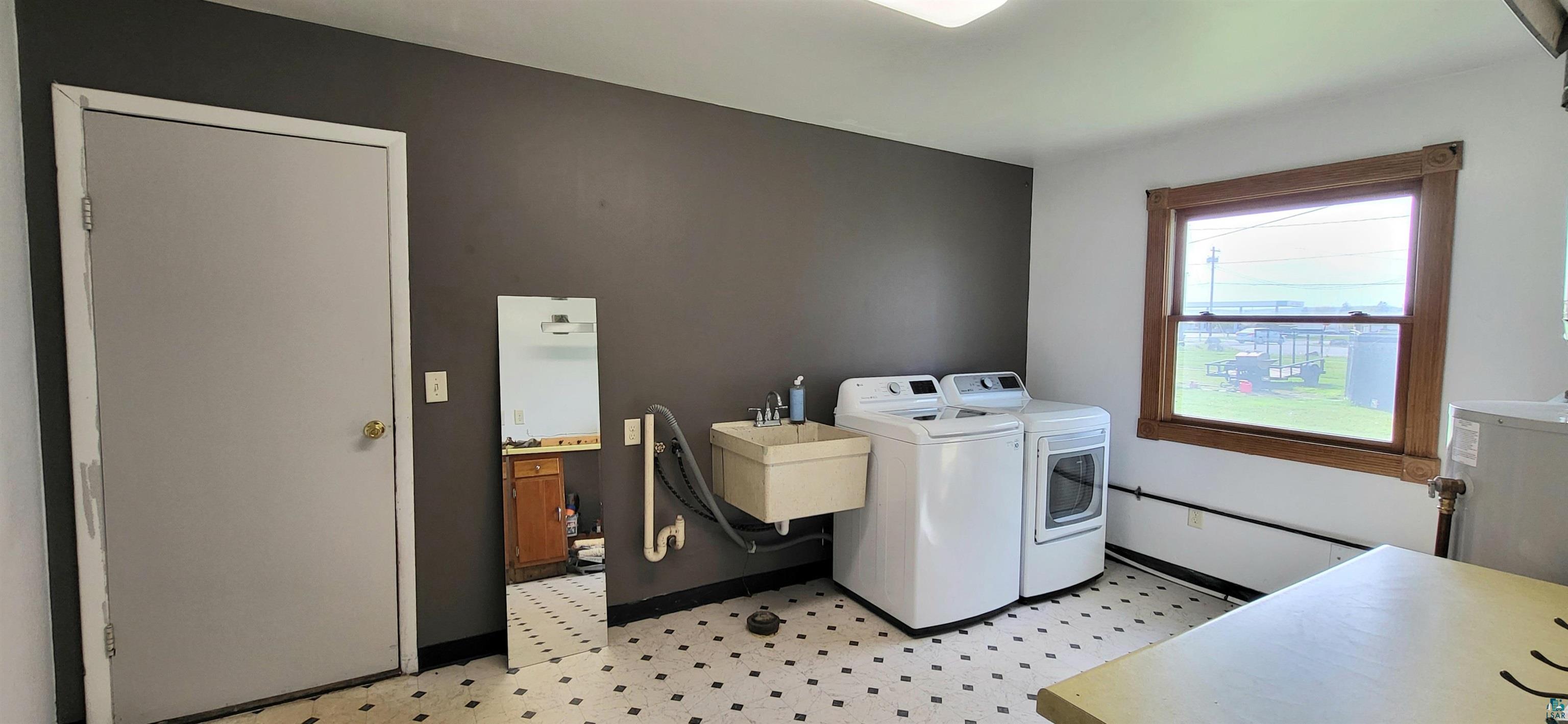 56 East 2nd Street Superior, WI 54880 - Photo 15 of 18 Spacious utility room featuring patterned floor tiles, a wall-mounted utility sink, and a wood-trimmed window