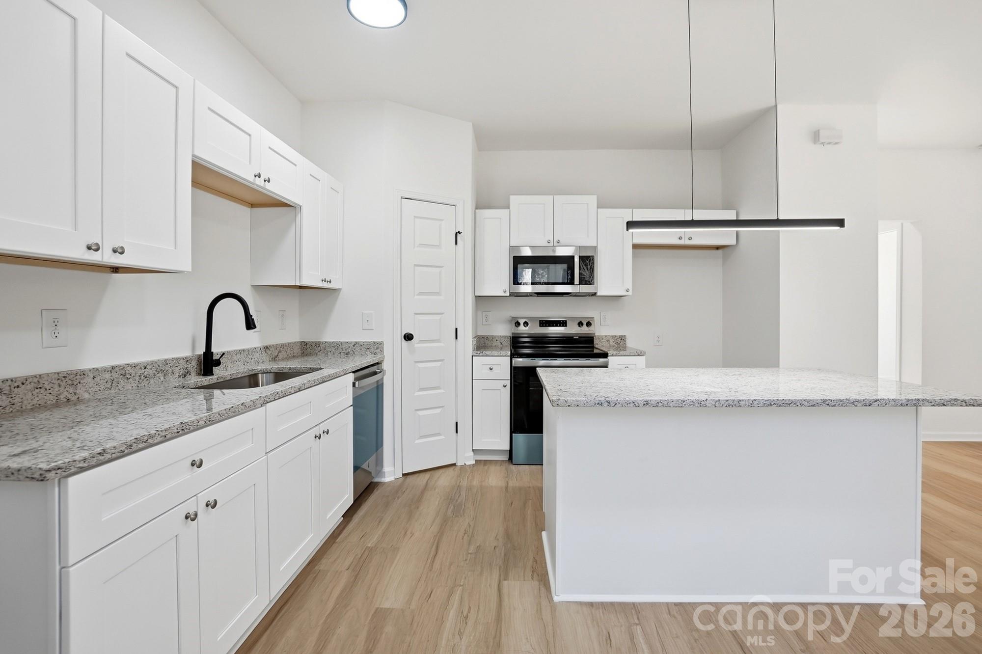 711 Adams Street Monroe, NC 28110 - Photo 12 of 25 a kitchen with kitchen island a sink stainless steel appliances and cabinets