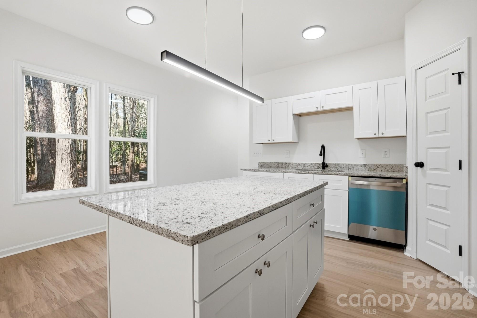 711 Adams Street Monroe, NC 28110 - Photo 15 of 25 a kitchen with a sink dishwasher a stove and white cabinets with wooden floor