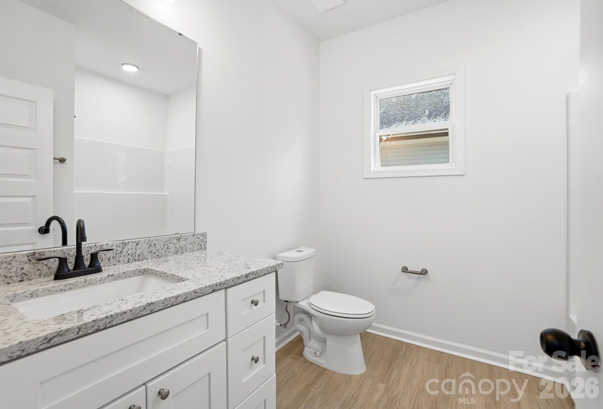 711 Adams Street Monroe, NC 28110 - Photo 18 of 25 a bathroom with a granite countertop sink toilet and a mirror