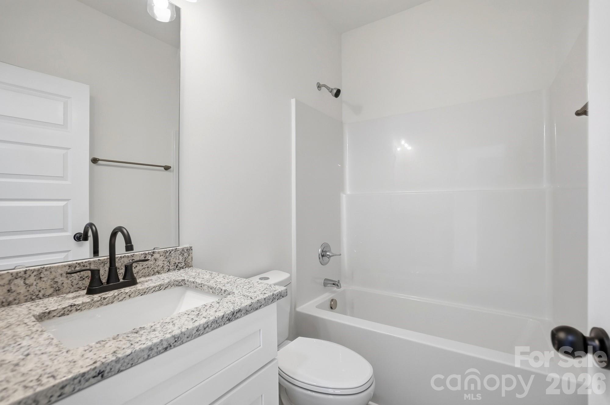 711 Adams Street Monroe, NC 28110 - Photo 21 of 25 a bathroom with a granite countertop sink toilet and shower