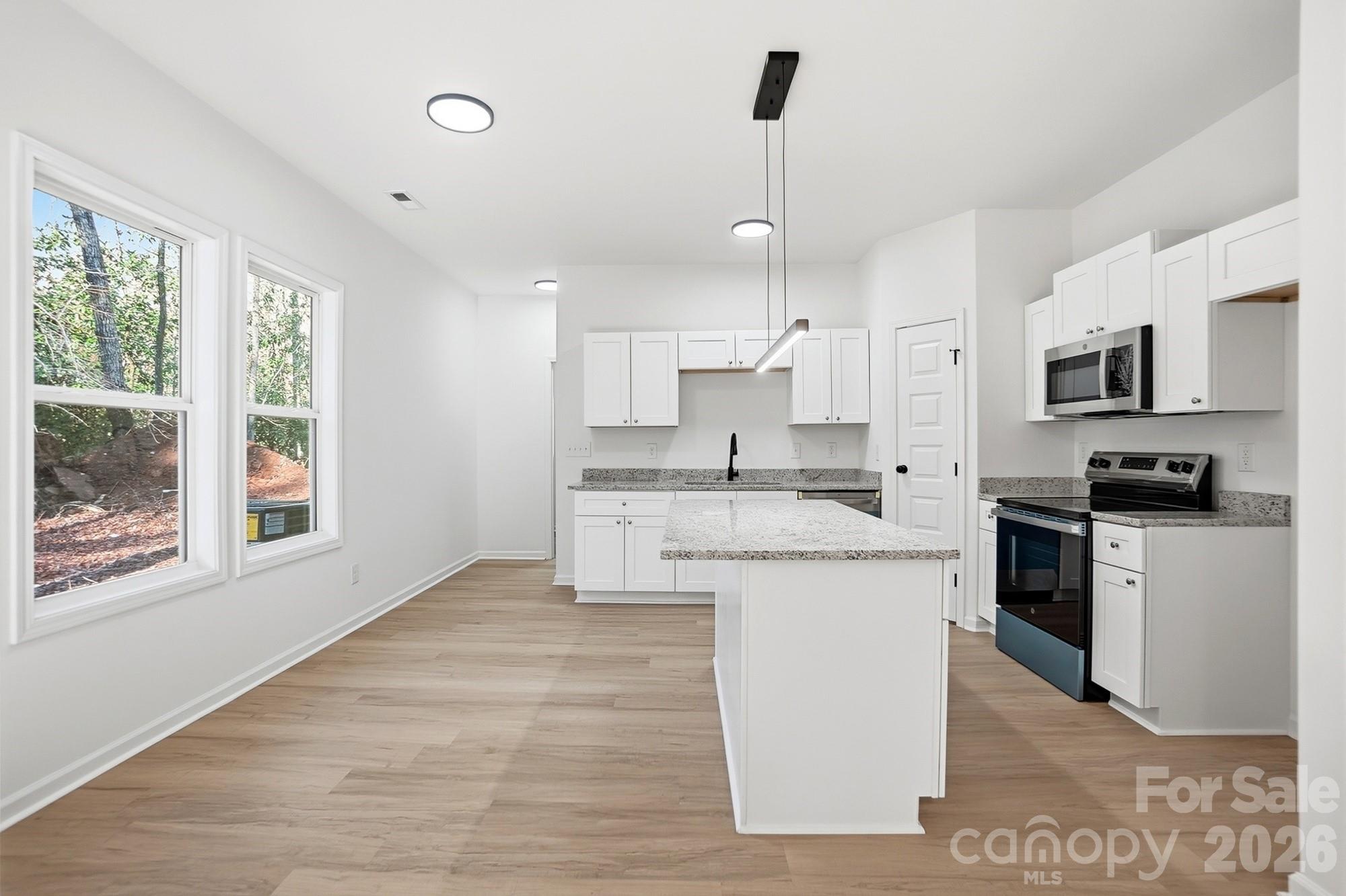 711 Adams Street Monroe, NC 28110 - Photo 10 of 25 a kitchen with kitchen island granite countertop a sink a counter space appliances and a window