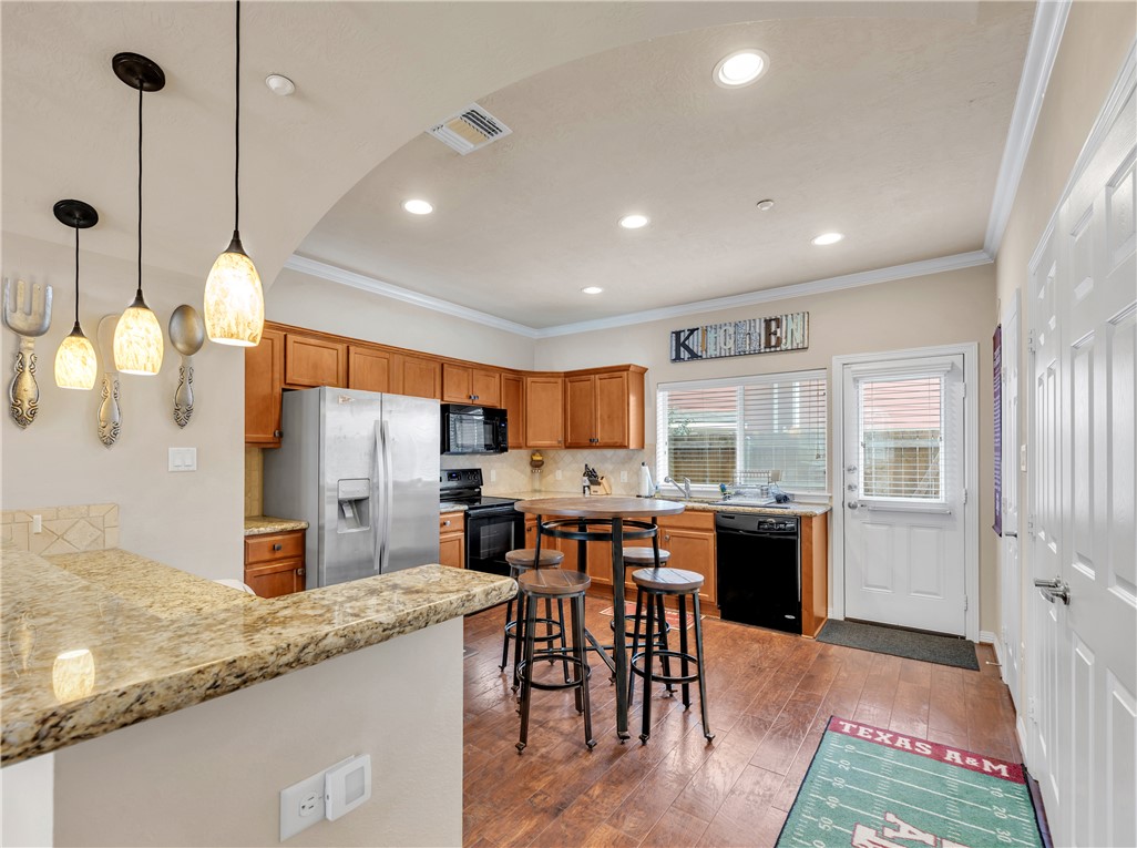 1198 Jones-Butler Road, Unit 2305 College Station, TX 77840 - Photo 6 of 25 a open kitchen with stainless steel appliances granite countertop a stove top oven a sink dishwasher a dining table and chairs with wooden floor