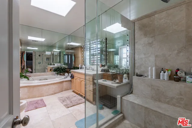 a bathroom with a tub a sink a mirror and a shower